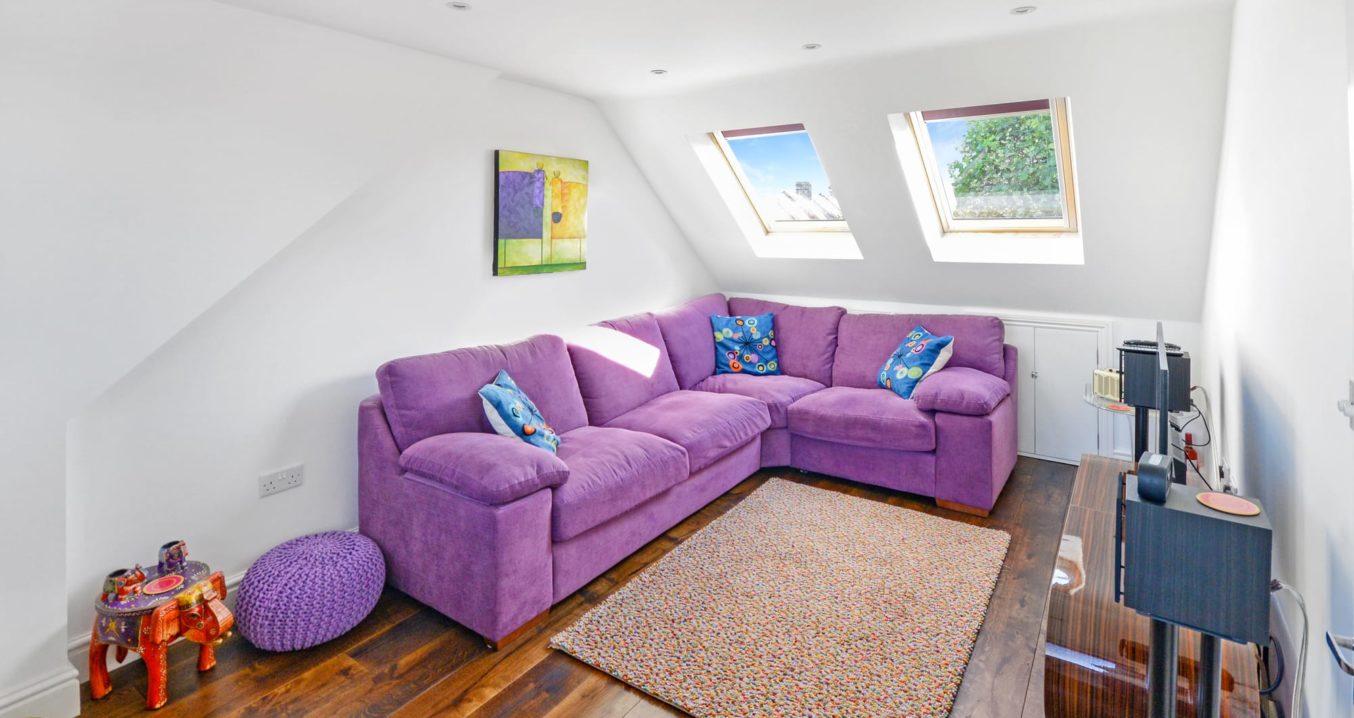 purple living room with a corner sofa in a Rear Dormer loft conversion in a home in Walthamstow East London, E17
