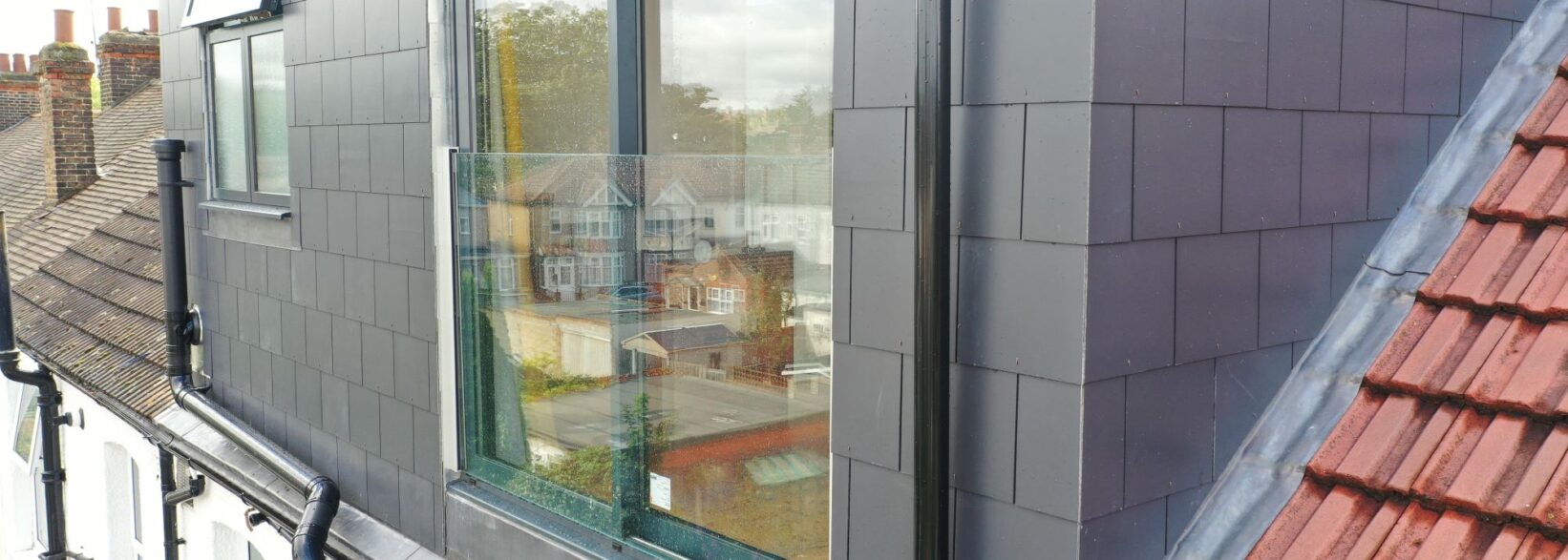 Outside of Hackney E9 property. Rear dormer loft with grey aluminium sliding doors with a frameless glass balcony