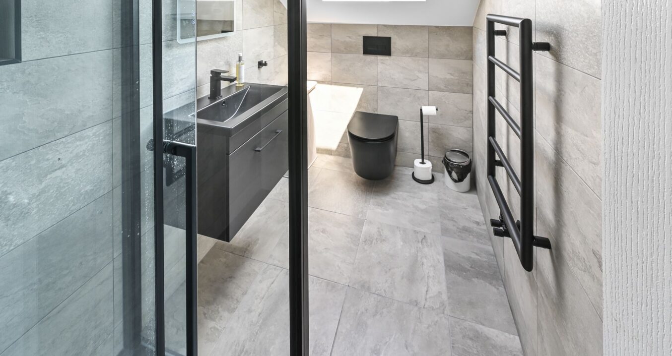 Modern ensuite bathroom in Barnet North London loft conversion with large format tiles, floating vanity, wall-hung toilet, skylight, and black fixtures