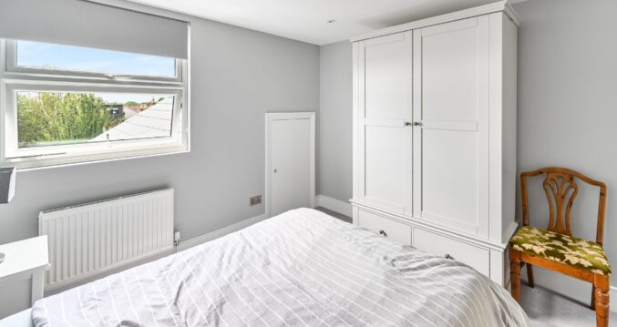 Clean and modern loft conversion bedroom with L-shaped dormer in Barnet North London featuring built-in wardrobes, with natural light.