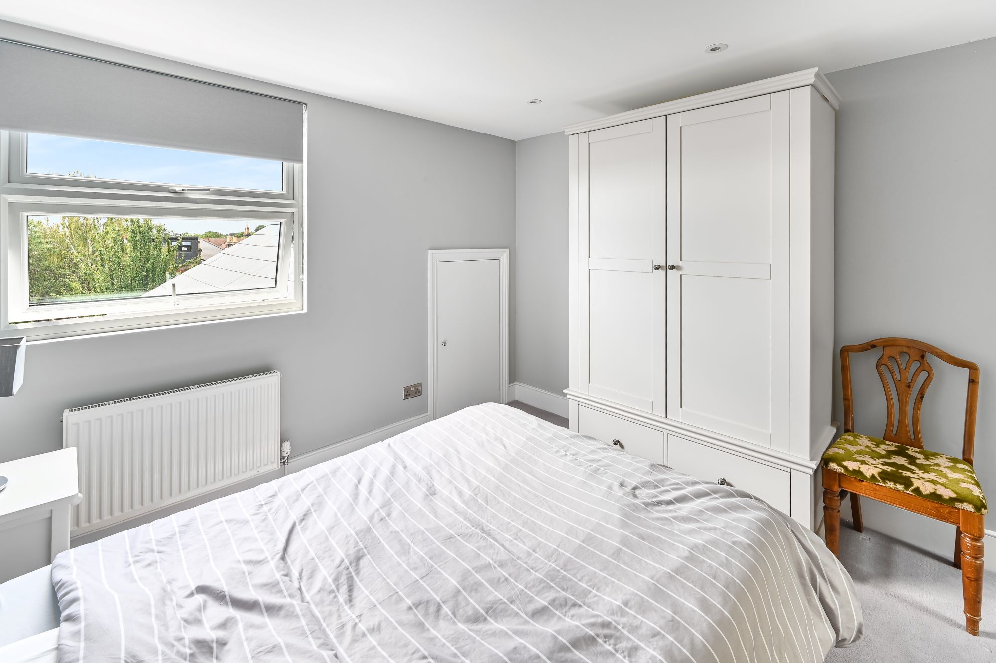 Clean and modern loft conversion bedroom with L-shaped dormer in Barnet North London featuring built-in wardrobes, with natural light.