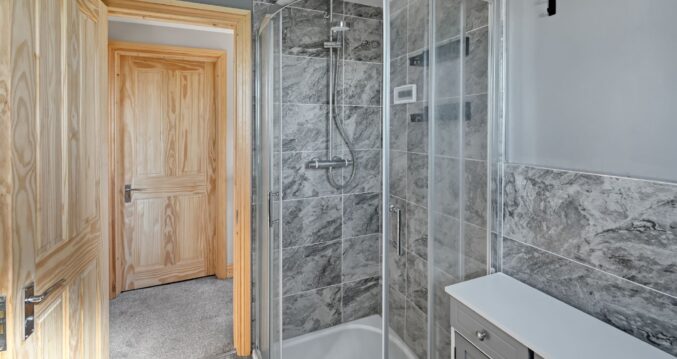 Corner walk-in shower with curved glass screen and bathtub in the modern bathroom of a Woolwich SE18 loft conversion
