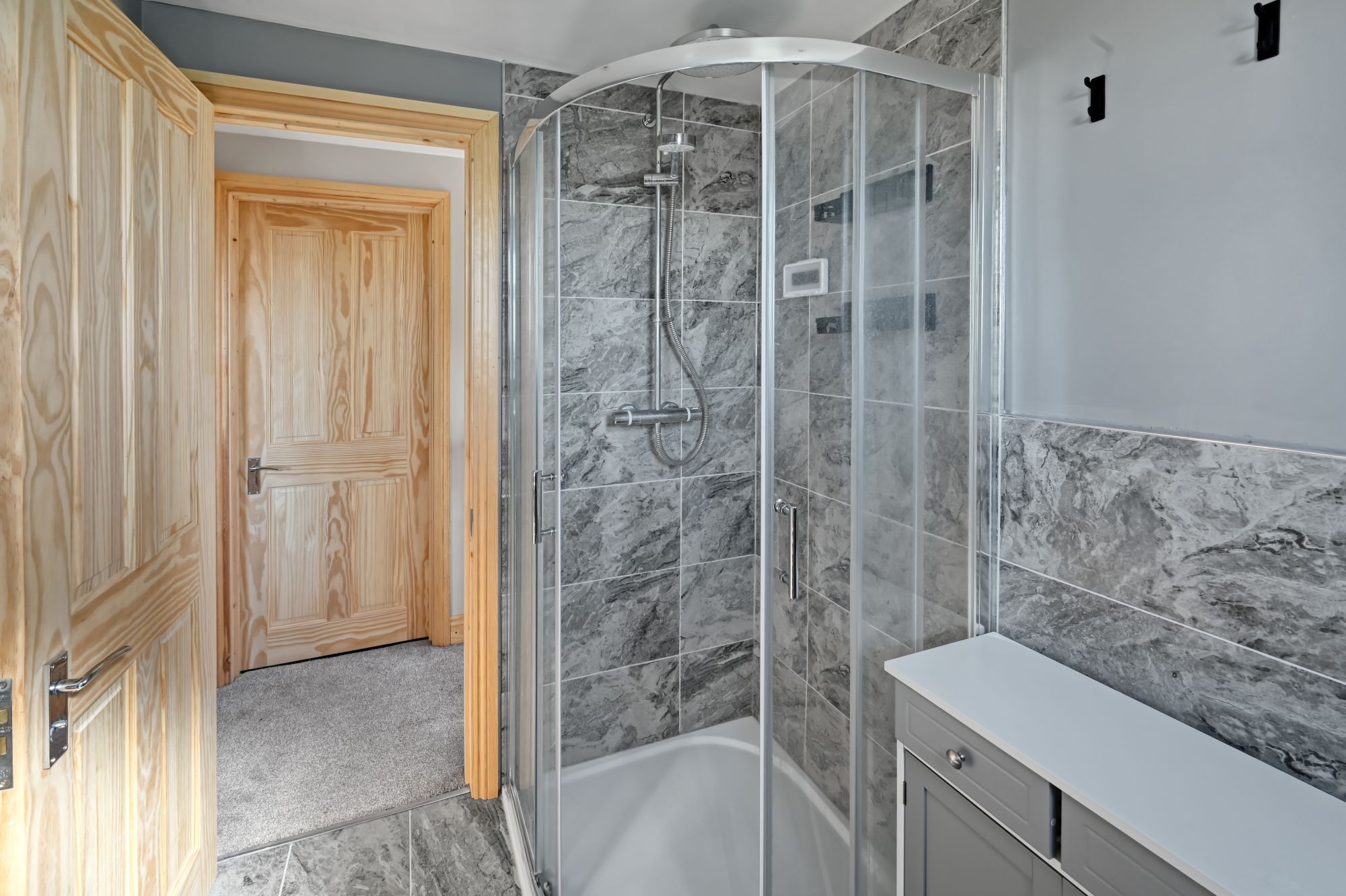 Corner walk-in shower with curved glass screen and bathtub in the modern bathroom of a Woolwich SE18 loft conversion