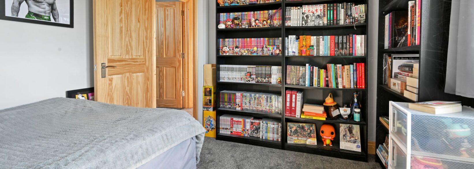 Extensive black shelving unit displaying a large manga and anime collection with figures and models in the Woolwich SE18 loft conversion bedroom