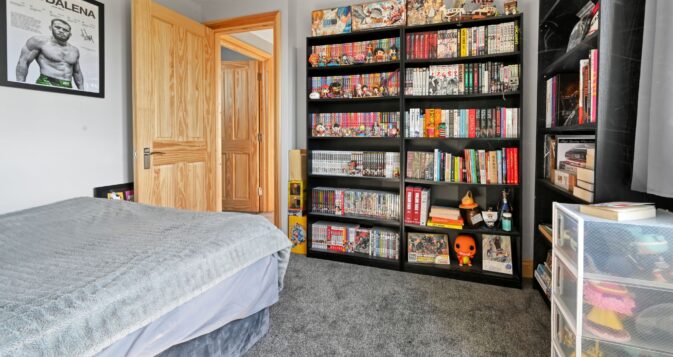 Extensive black shelving unit displaying a large manga and anime collection with figures and models in the Woolwich SE18 loft conversion bedroom