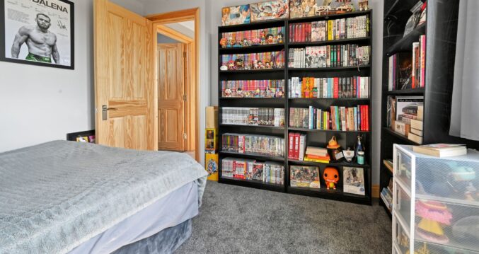 Extensive black shelving unit displaying a large manga and anime collection with figures and models in the Woolwich SE18 loft conversion bedroom