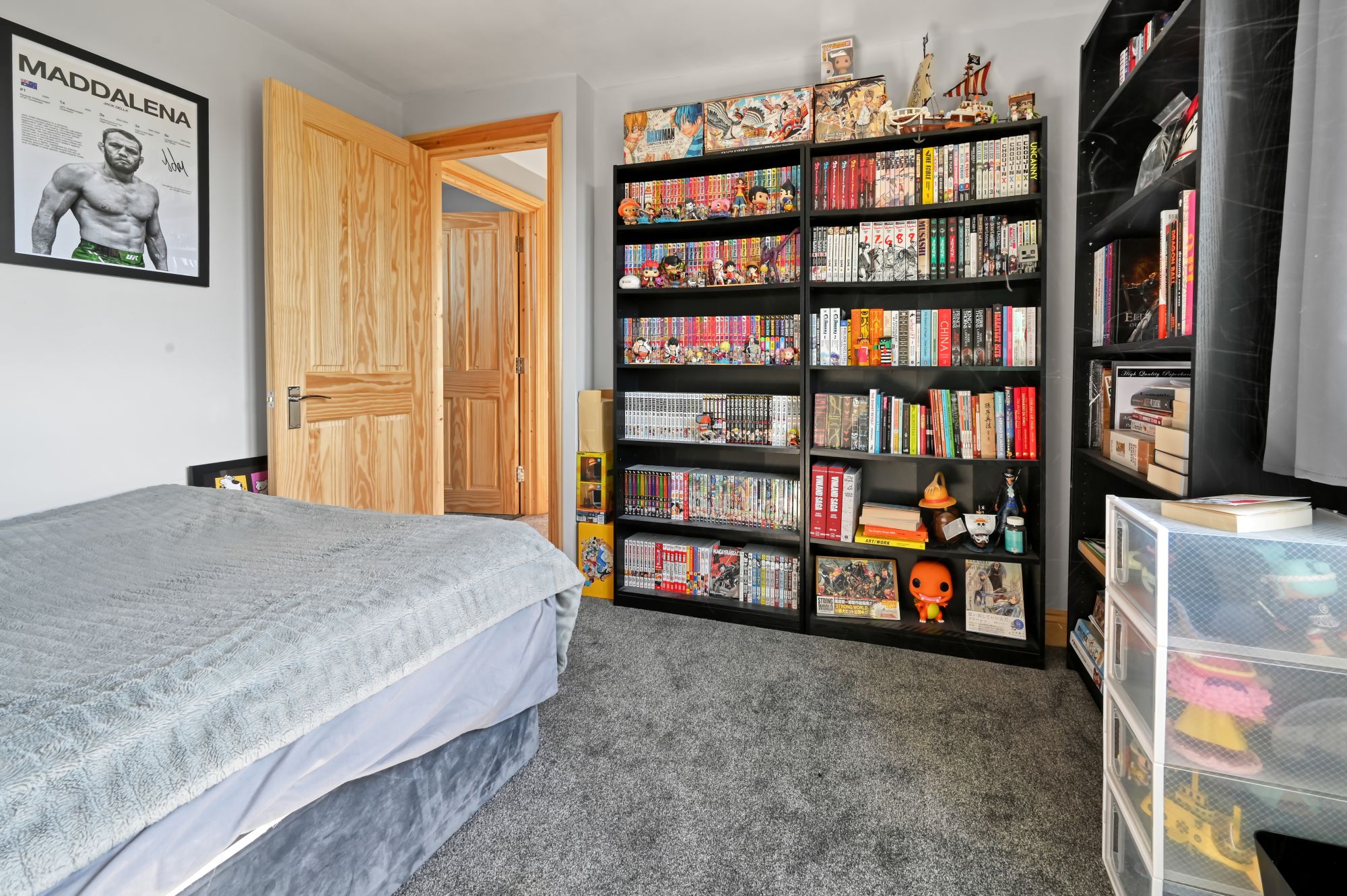 Extensive black shelving unit displaying a large manga and anime collection with figures and models in the Woolwich SE18 loft conversion bedroom