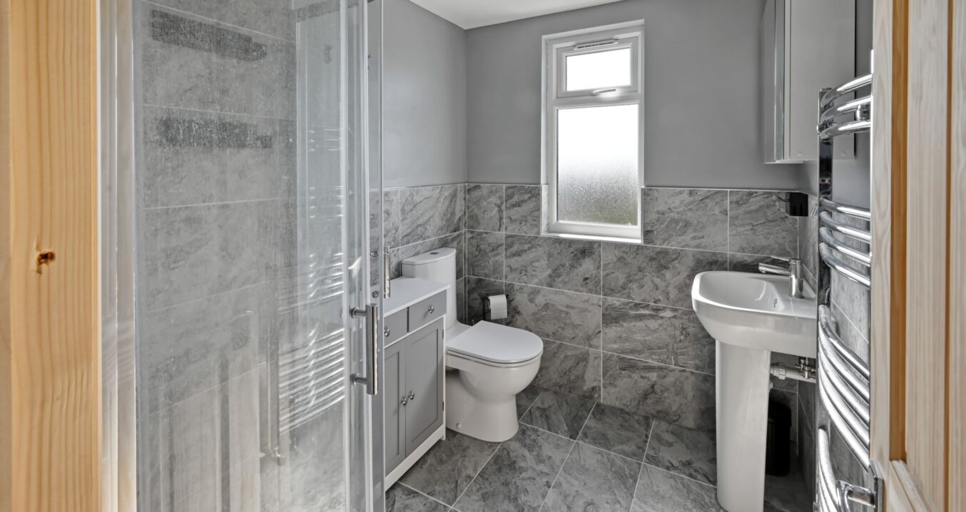 Contemporary grey marble-effect bathroom featuring a walk-in shower, toilet, and vanity unit in a newly converted loft in Woolwich SE18