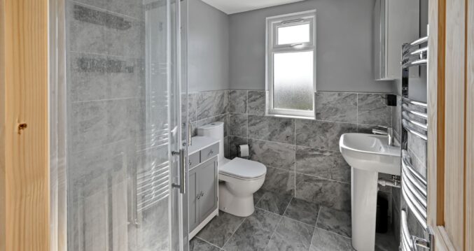 Contemporary grey marble-effect bathroom featuring a walk-in shower, toilet, and vanity unit in a newly converted loft in Woolwich SE18