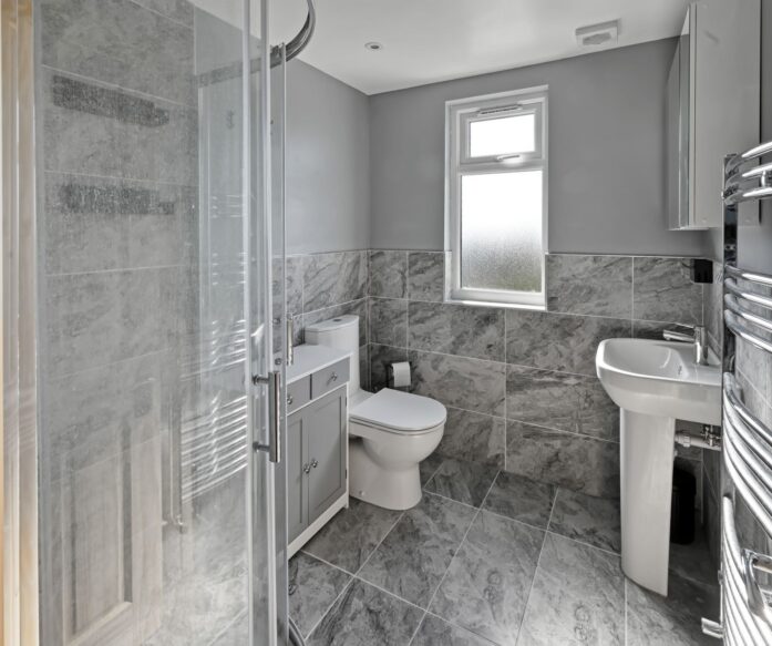 Contemporary grey marble-effect bathroom featuring a walk-in shower, toilet, and vanity unit in a newly converted loft in Woolwich SE18