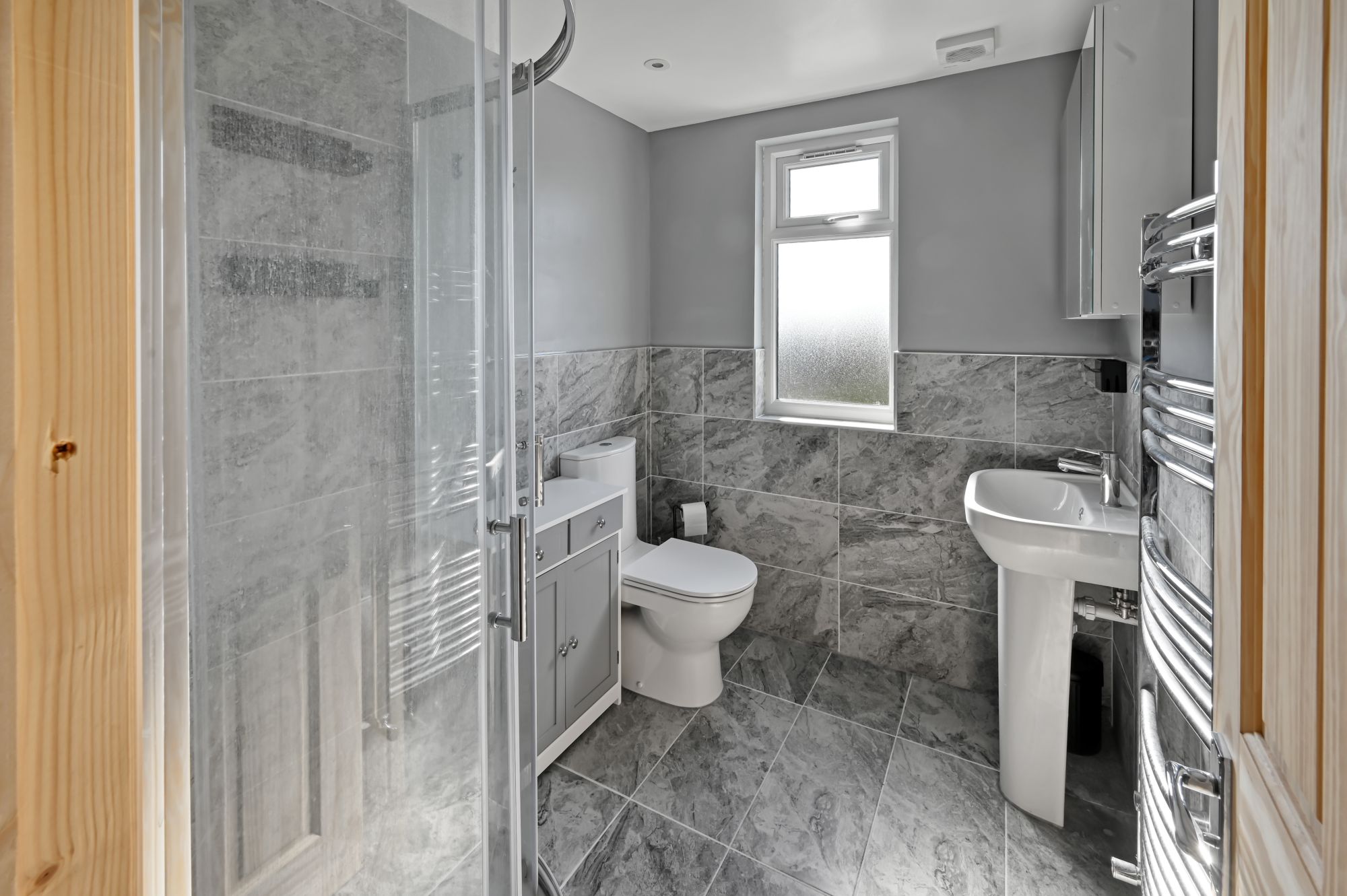 Contemporary grey marble-effect bathroom featuring a walk-in shower, toilet, and vanity unit in a newly converted loft in Woolwich SE18