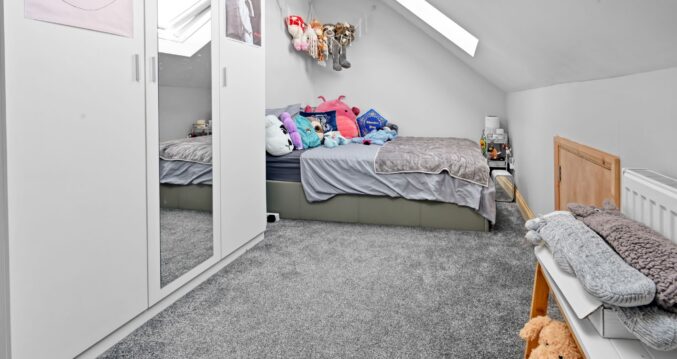 Modern kids’ bedroom in loft conversion with large white mirrored wardrobe, single bed, and multiple skylights in Woolwich SE18