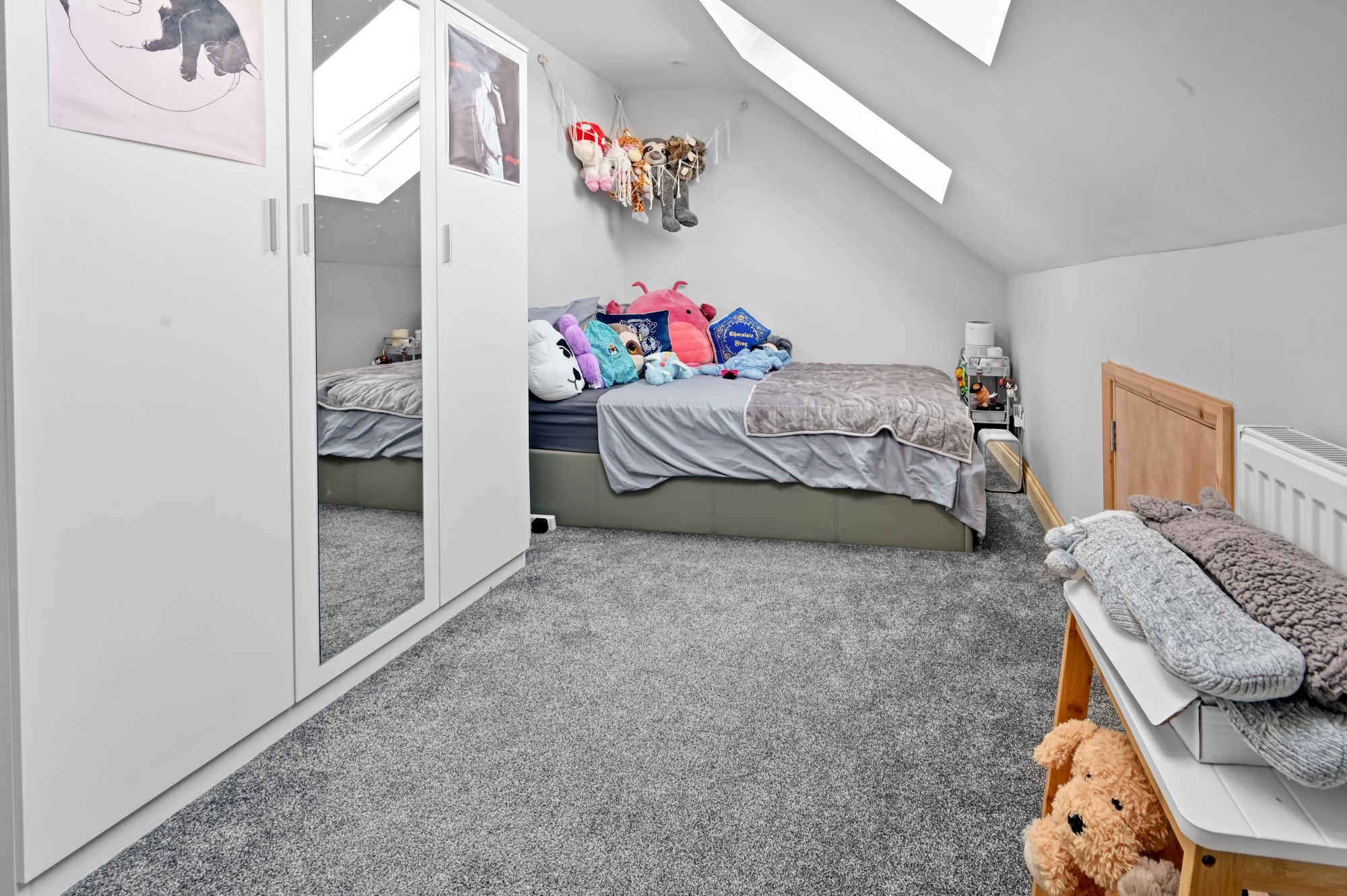 Modern kids’ bedroom in loft conversion with large white mirrored wardrobe, single bed, and multiple skylights in Woolwich SE18