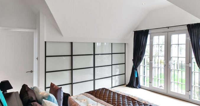 Contemporary hip to gable loft conversion bedroom in Barnet featuring black framed sliding wardrobes and bifold doors