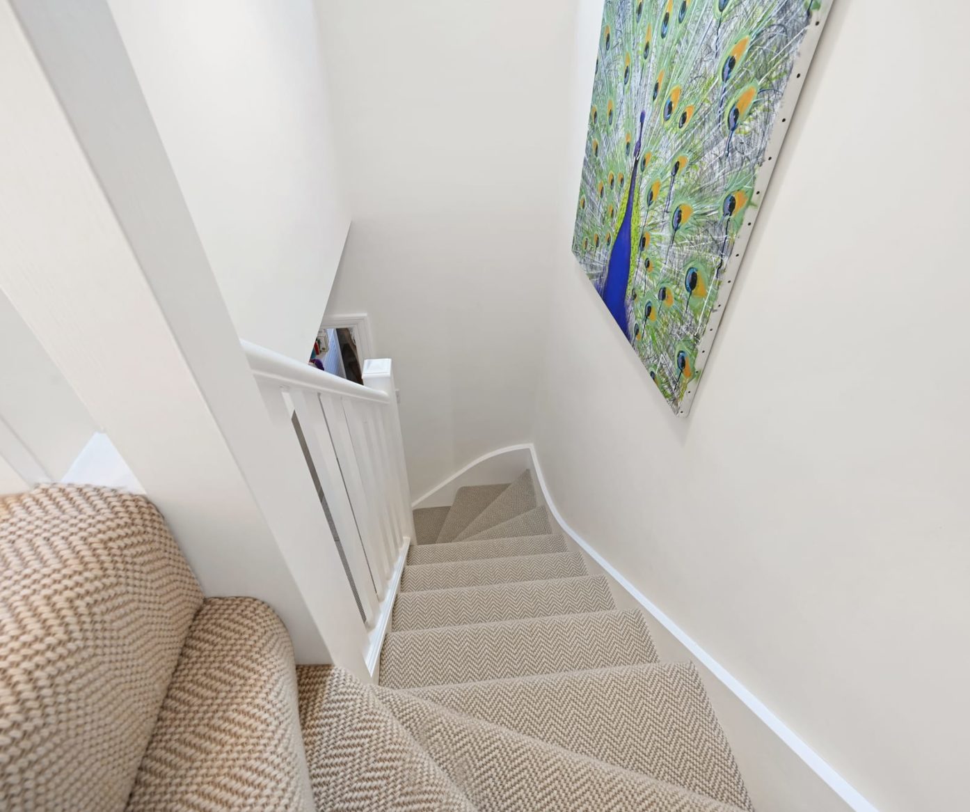 Elegant curved staircase featuring colourful peacock artwork in a Walthamstow loft conversion