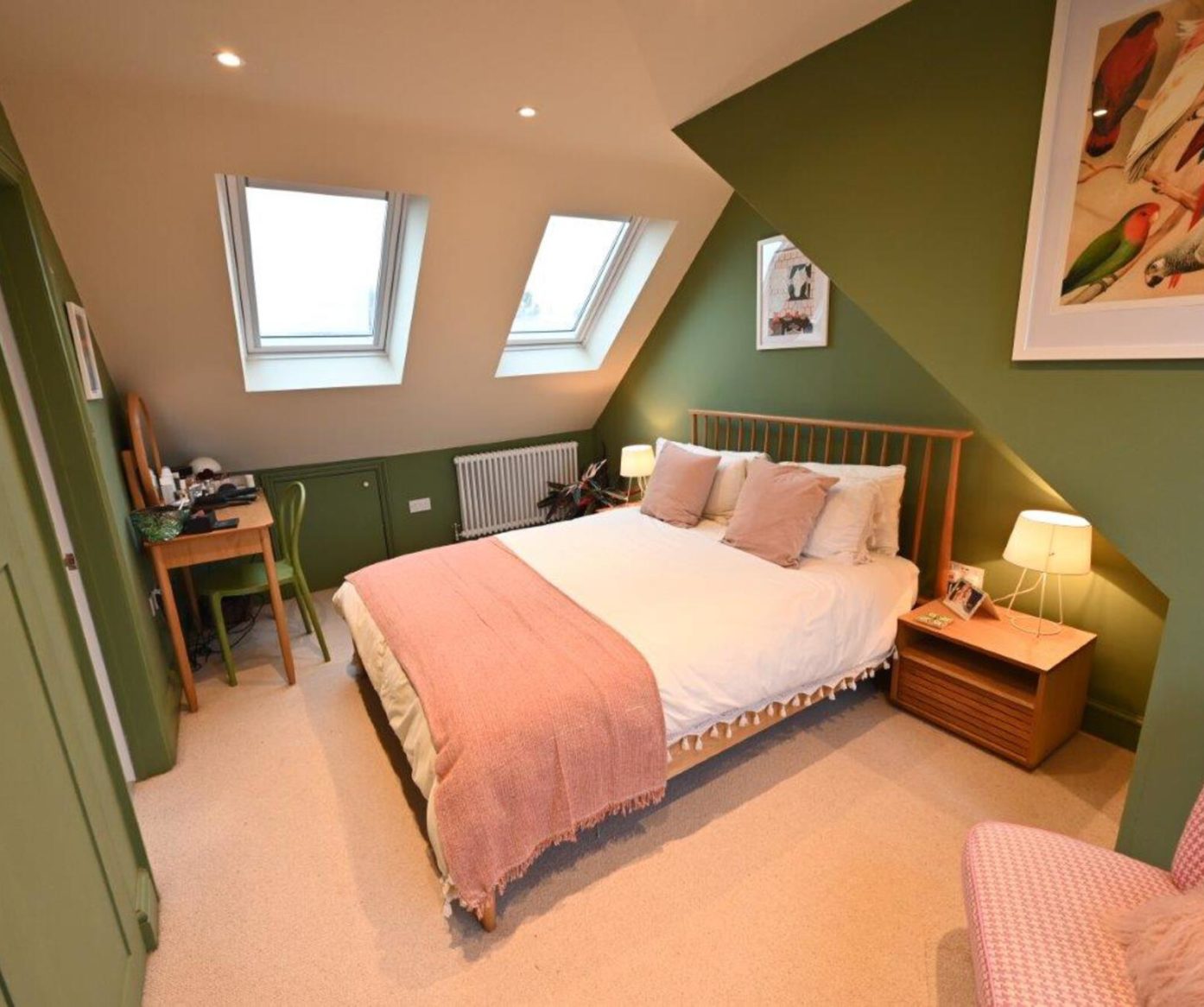 Green feature wall bedroom with wooden bed, desk and roof windows in a Walthamstow loft conversion