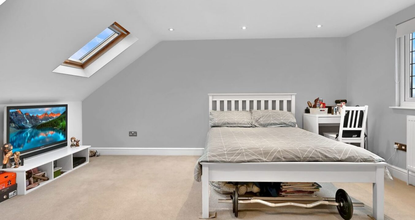 Large dormer loft bedroom in Harrow with grey décor, skylight, desk area and open floor space