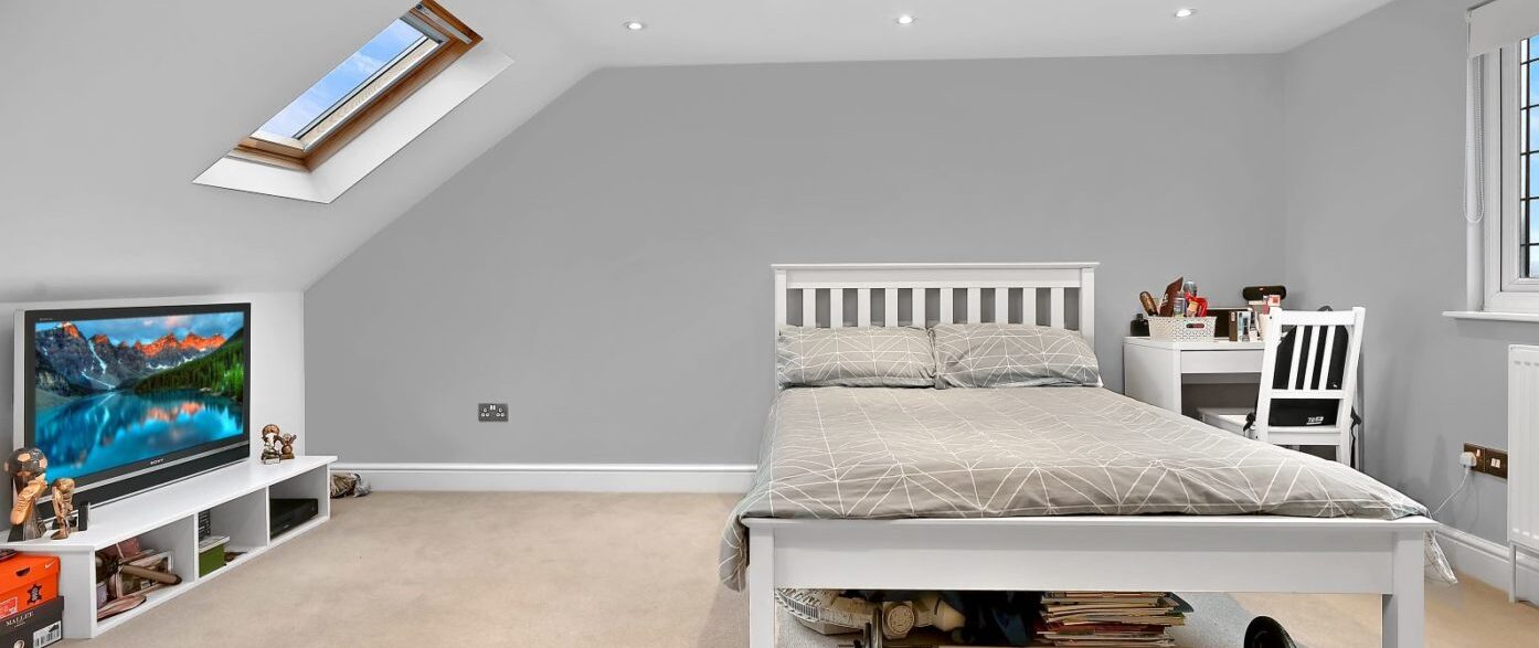 Large dormer loft bedroom in Harrow with grey décor, skylight, desk area and open floor space