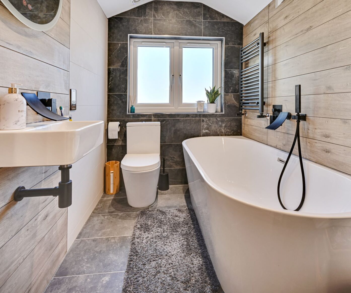 Family bathroom in a Beckenham BR3 loft conversion with bath, modern tiles, black fittings and window