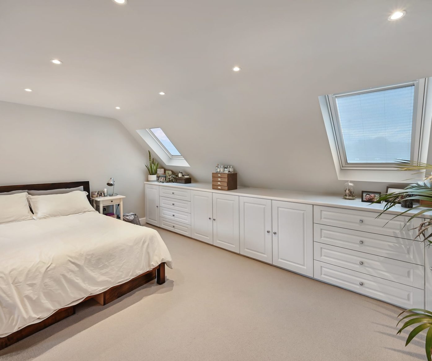 Fitted bedroom loft conversion in Beckenham BR3 with white storage, bed, roof windows and soft carpet