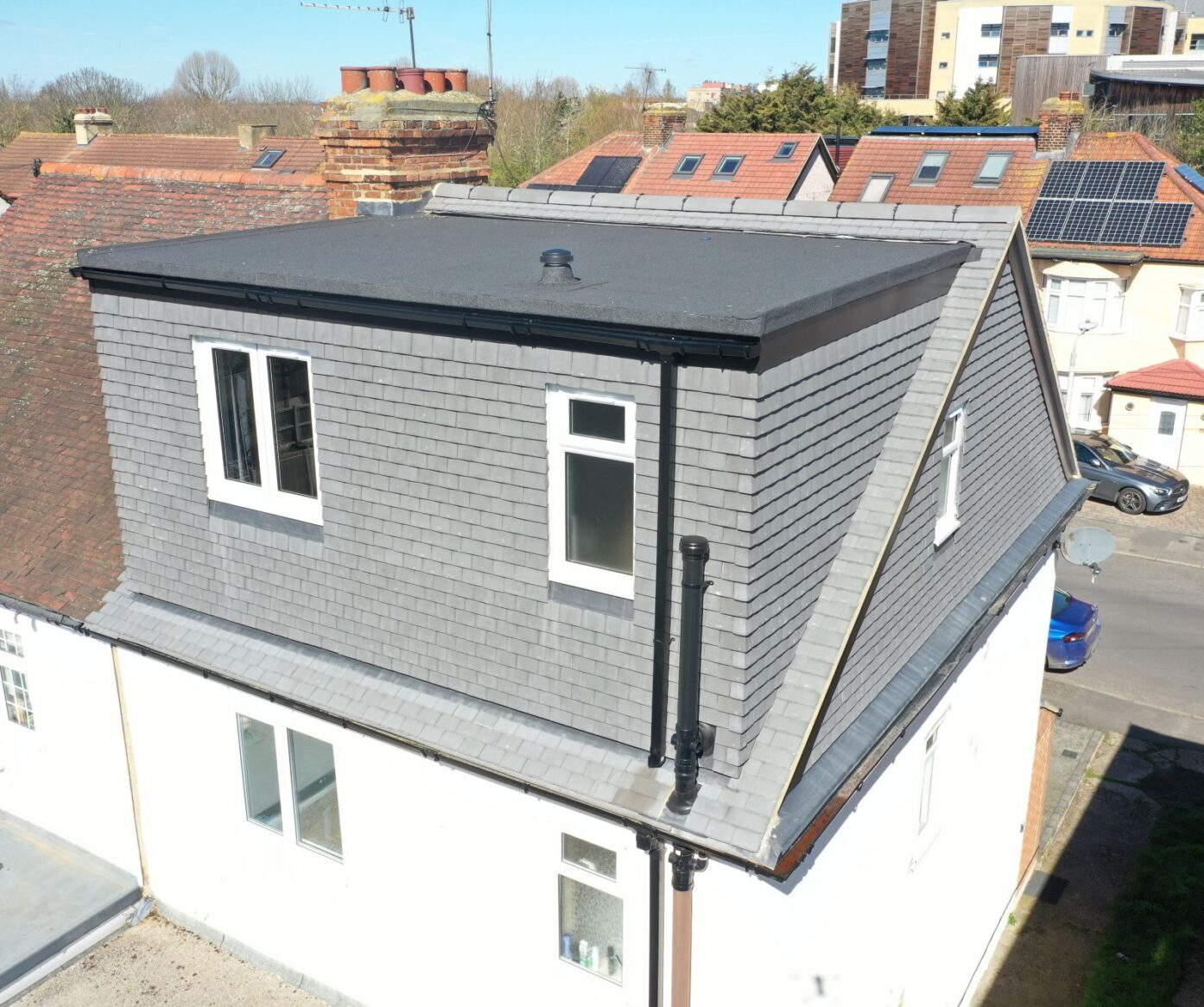 Exterior view of a rear dormer loft conversion in Beckenham BR3 with grey cladding and white windows