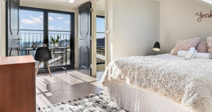 Contemporary loft conversion bedroom with large balcony bifold doors, natural light and city views in Edgware