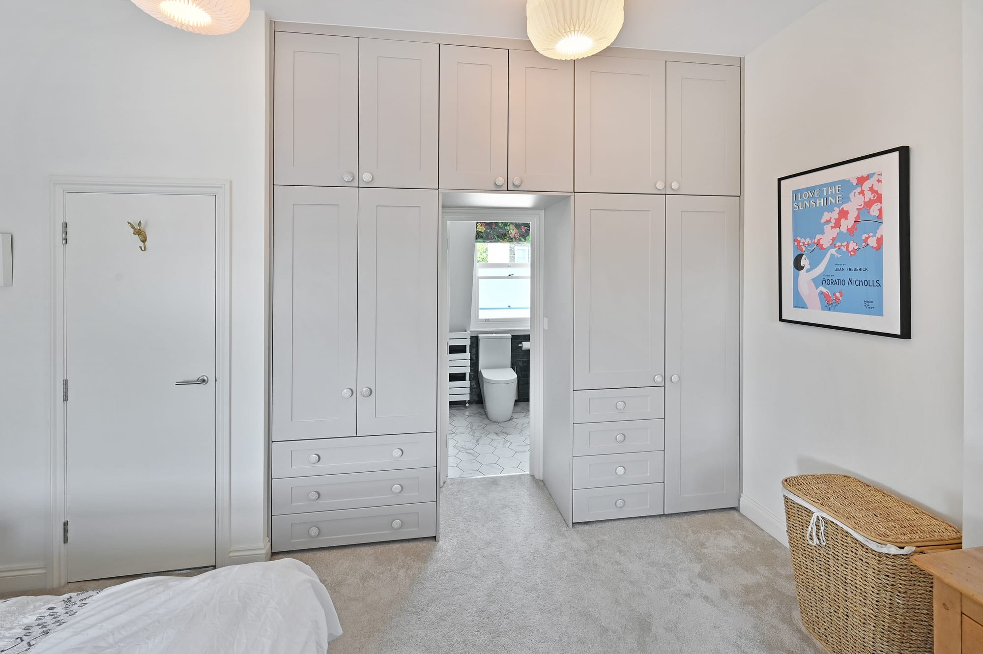 Bedroom in a Borehamwood loft conversion with fitted wardrobes and en suite doorway