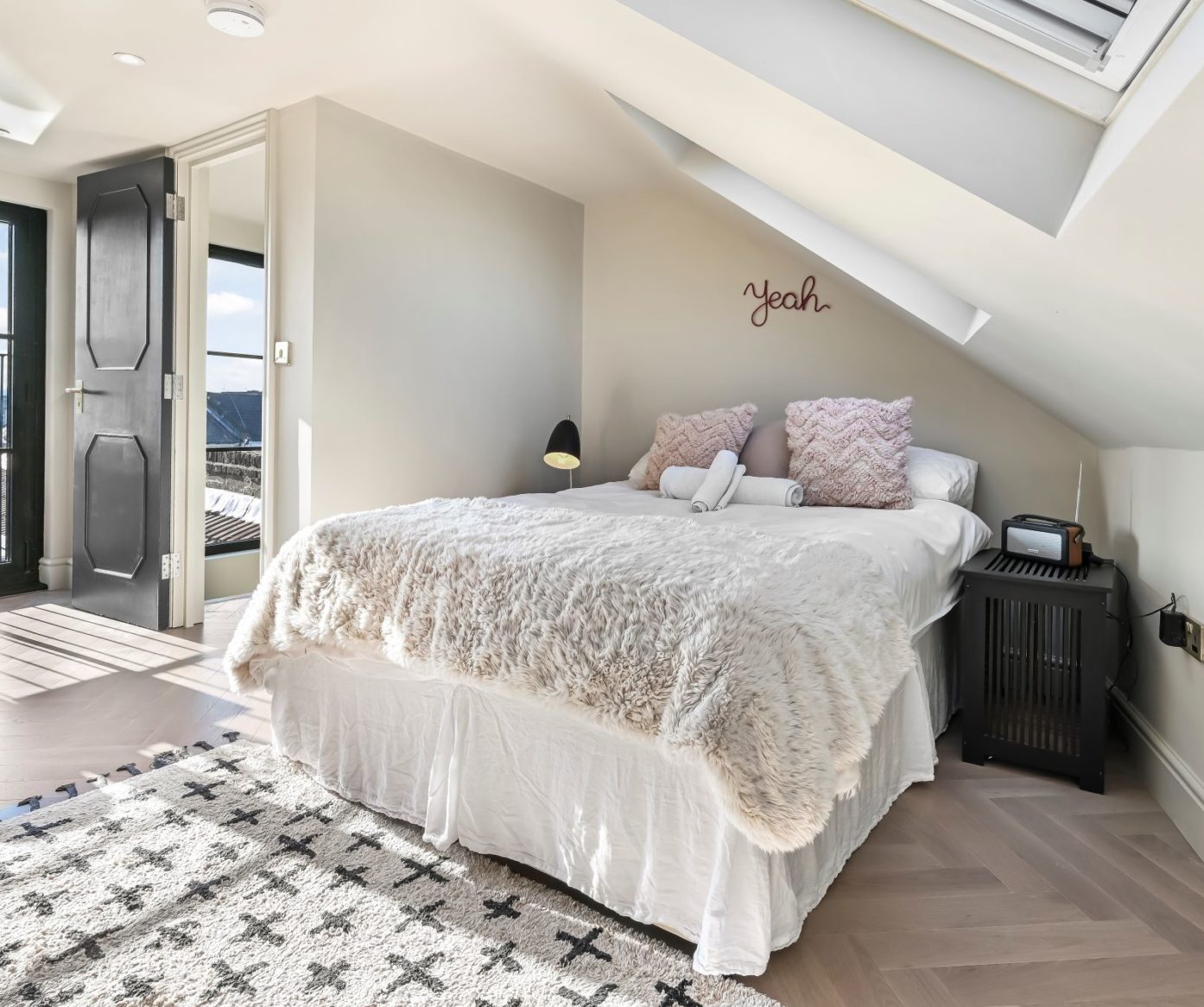 Master bedroom suite in a Borehamwood loft conversion with sloped ceiling and Velux roof window