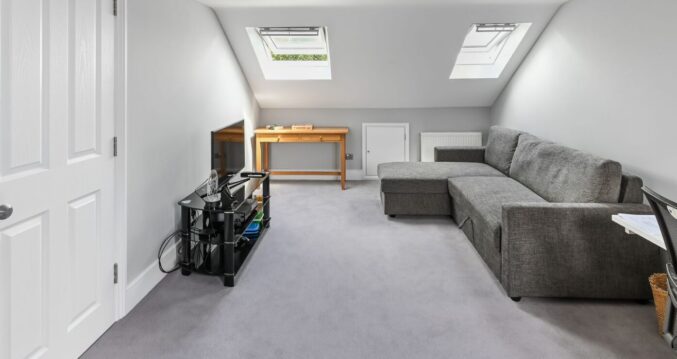 Dormer loft conversion in Bromley with Velux windows, grey carpet and lounge seating area