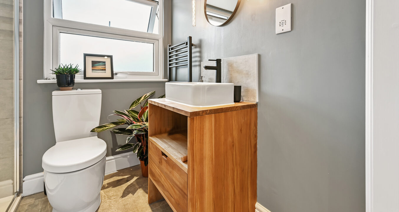 En suite shower room in Bromley loft conversion with timber vanity unit, grey walls and modern fittings