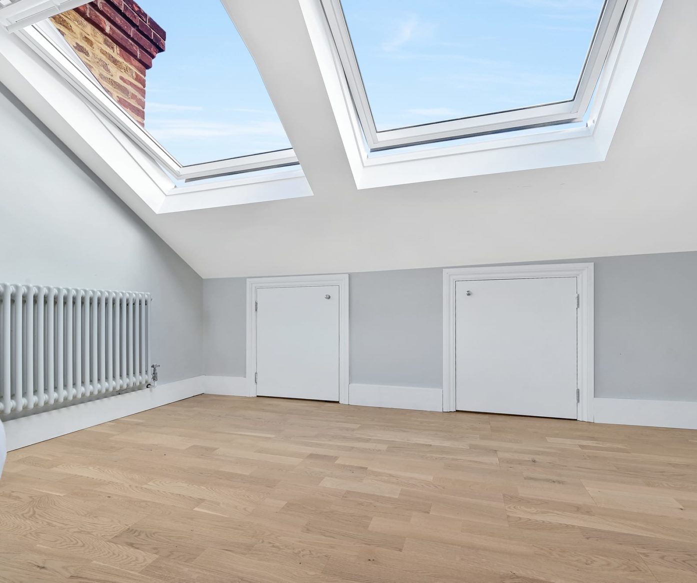 Loft conversion room in Bromley with oak flooring, twin rooflights and built-in eaves storage