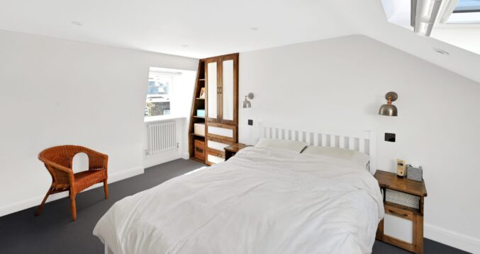 Master bedroom loft conversion in Bromley with fitted wardrobes, sloped ceiling and bespoke built-in storage