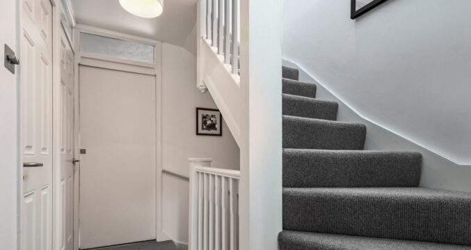 Loft conversion staircase in Bromley with grey carpet, white balustrade and modern landing area