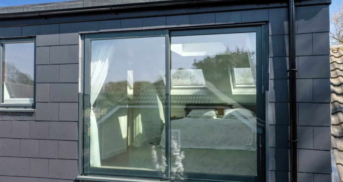 Rear dormer loft conversion in Greenwich with slate cladding and large sliding glass doors