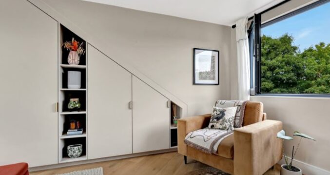 Loft conversion bedroom in Mill Hill with bespoke eaves cupboards, fitted shelving and bright modern finish