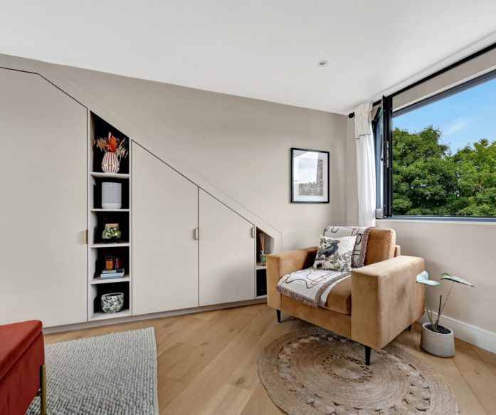 Loft conversion bedroom in Mill Hill with bespoke eaves cupboards, fitted shelving and bright modern finish