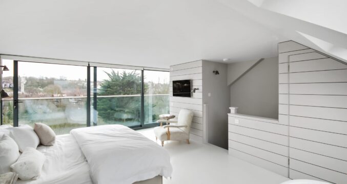 Master bedroom loft conversion in Sidcup with large glazed doors and bright modern interior design