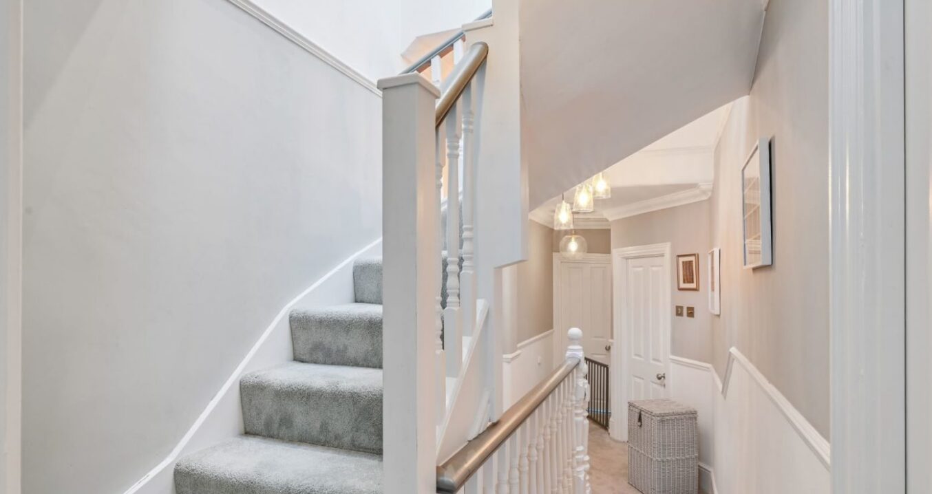 carpeted loft staircase and landing area with white balustrade in Kensal Rise property