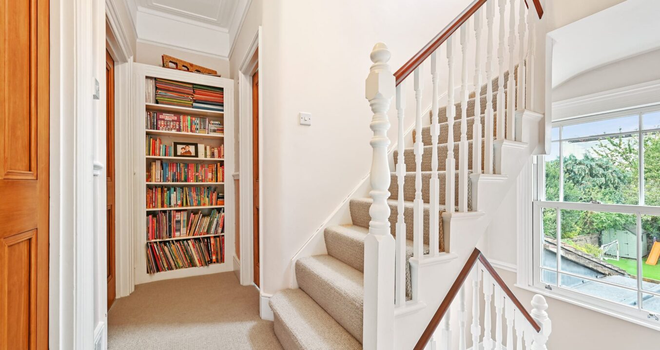 Loft conversion staircase with white balustrade and built-in bookshelf in Leyton.