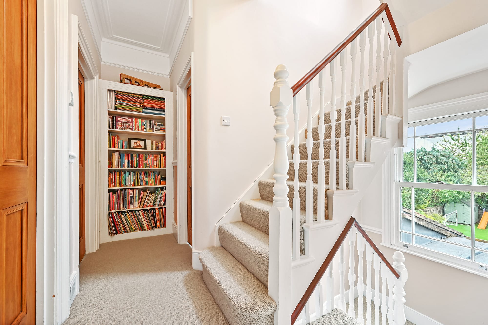 Loft conversion staircase with white balustrade and built-in bookshelf in Leyton.