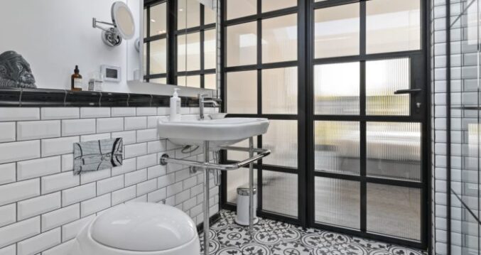 Stylish loft conversion en suite bathroom in Stoke Newington with patterned floor tiles, black framed shower screen and white suite