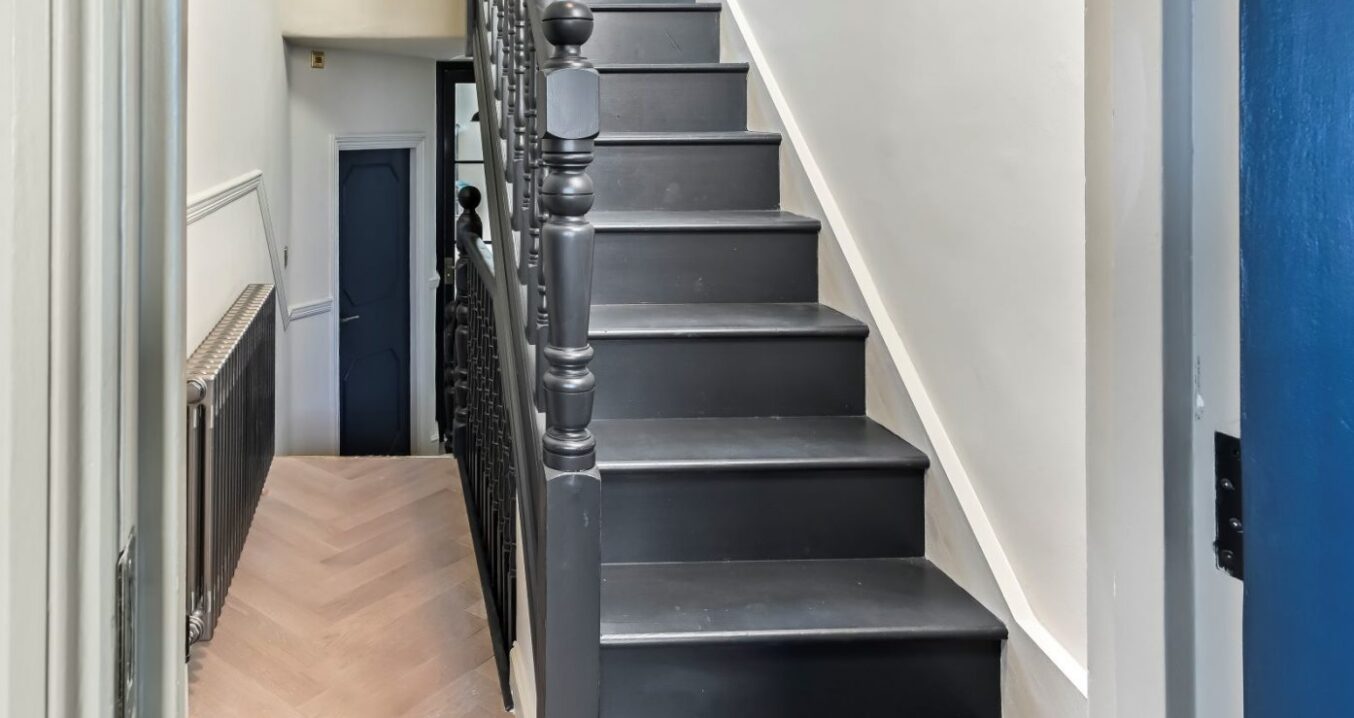 Dark timber staircase in Woolwich loft conversion with traditional balustrade and herringbone hallway flooring