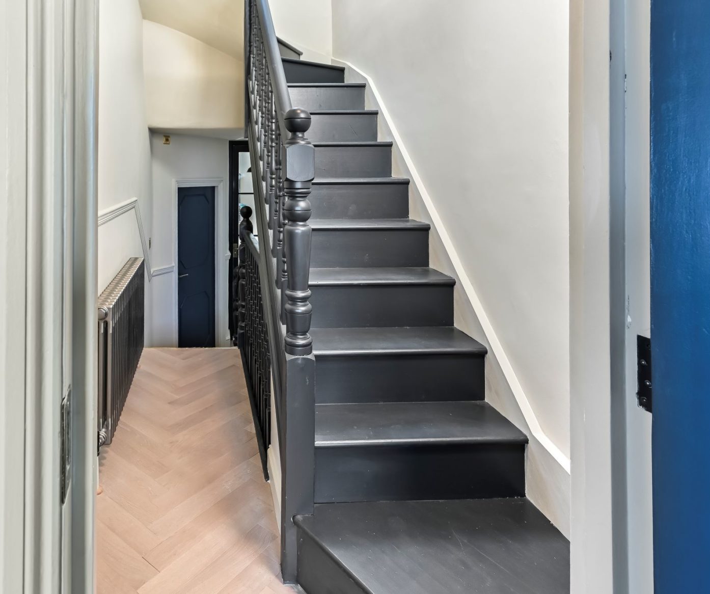 Dark timber staircase in Woolwich loft conversion with traditional balustrade and herringbone hallway flooring