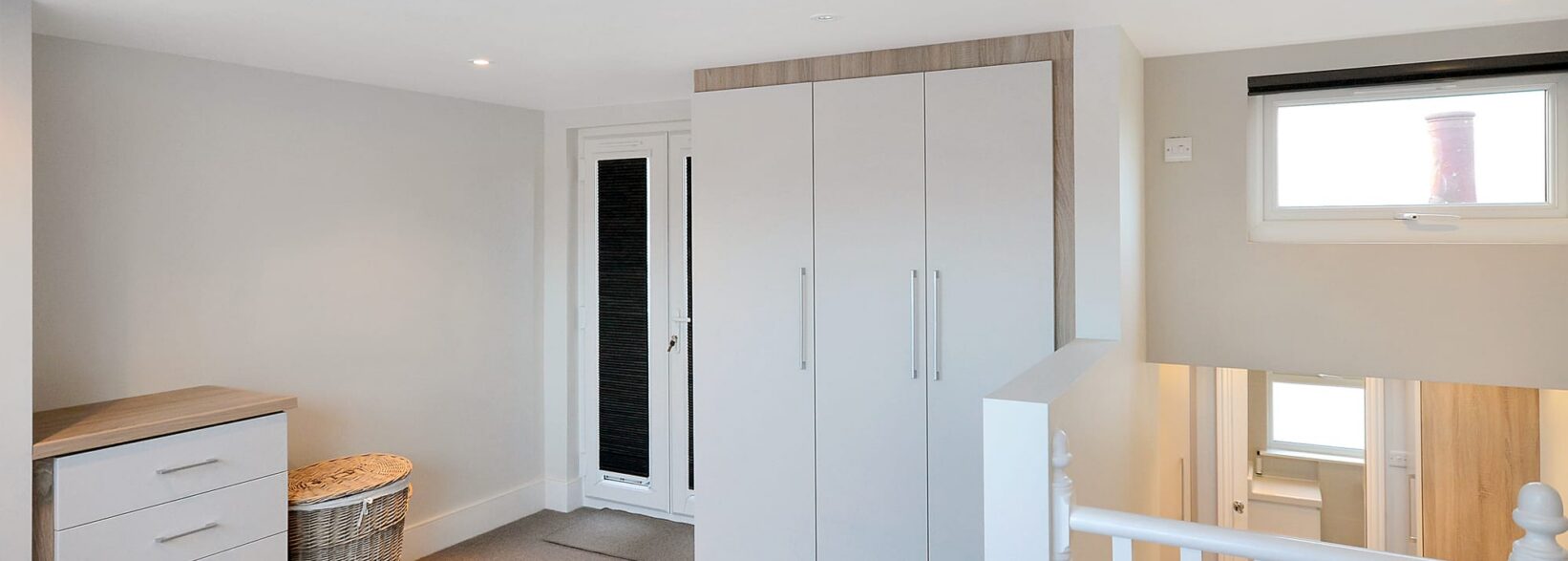 Loft landing bedroom area in Woolwich with fitted wardrobes, carpet flooring and bright upper floor access