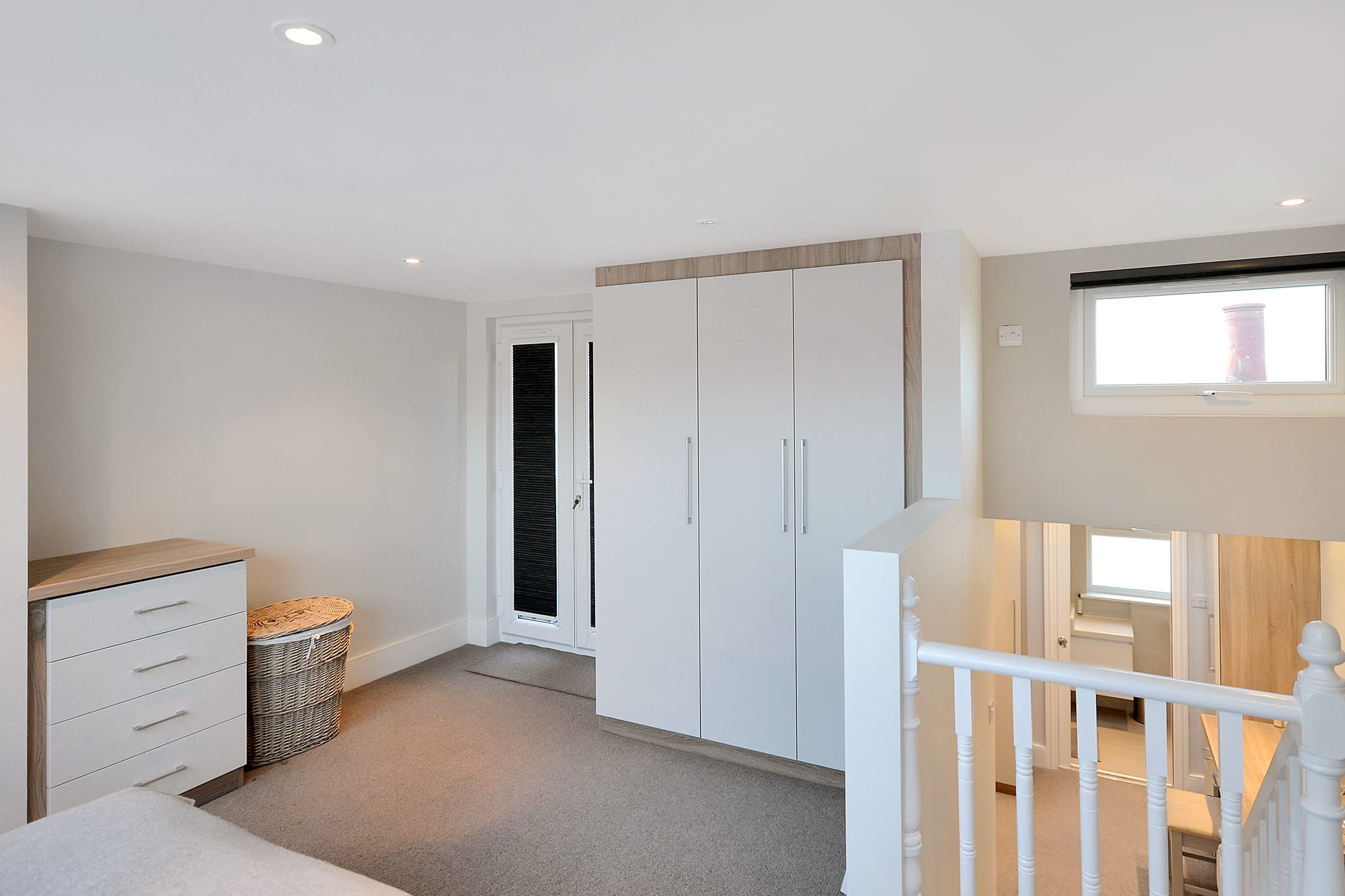 Loft landing bedroom area in Woolwich with fitted wardrobes, carpet flooring and bright upper floor access