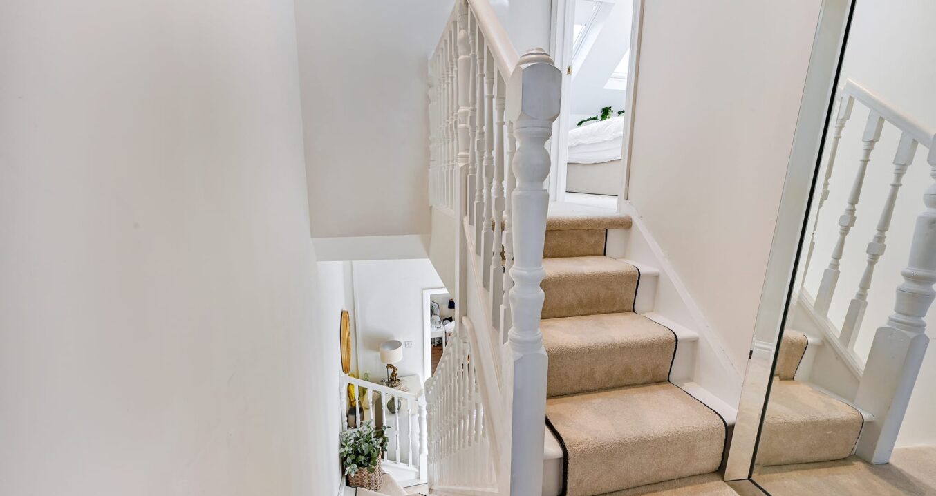 White staircase leading to loft conversion master suite in Woolwich with carpeted steps and bright landing