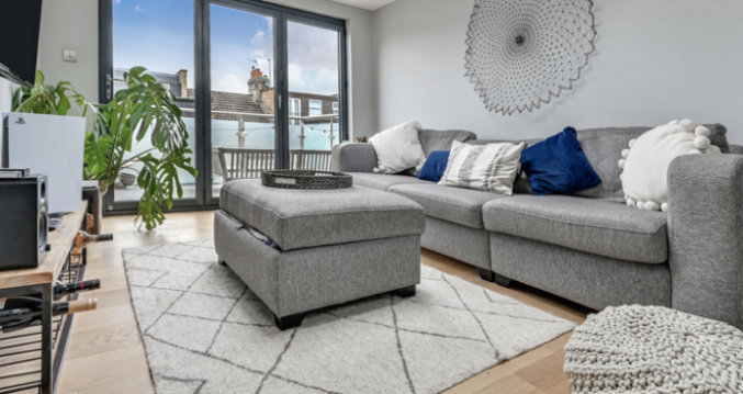 Modern grey sofa living room in Leyton loft conversion with balcony doors.