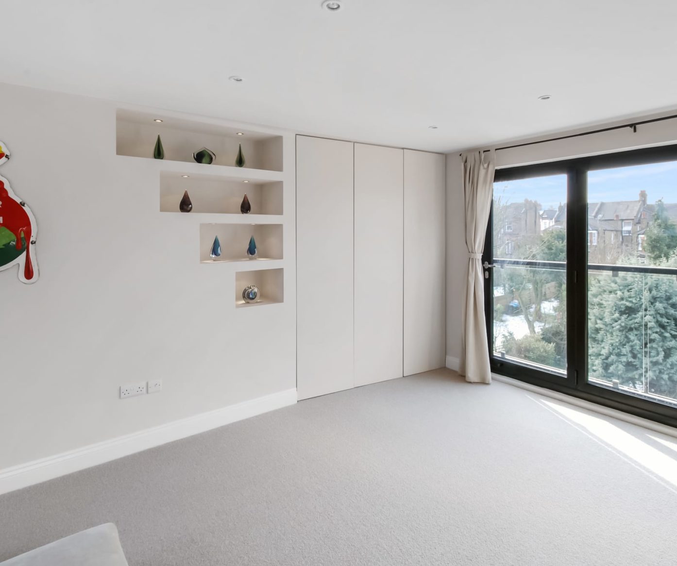 Hip to gable loft conversion modern bedroom in Barnet with bifold doors and full height white wardrobes