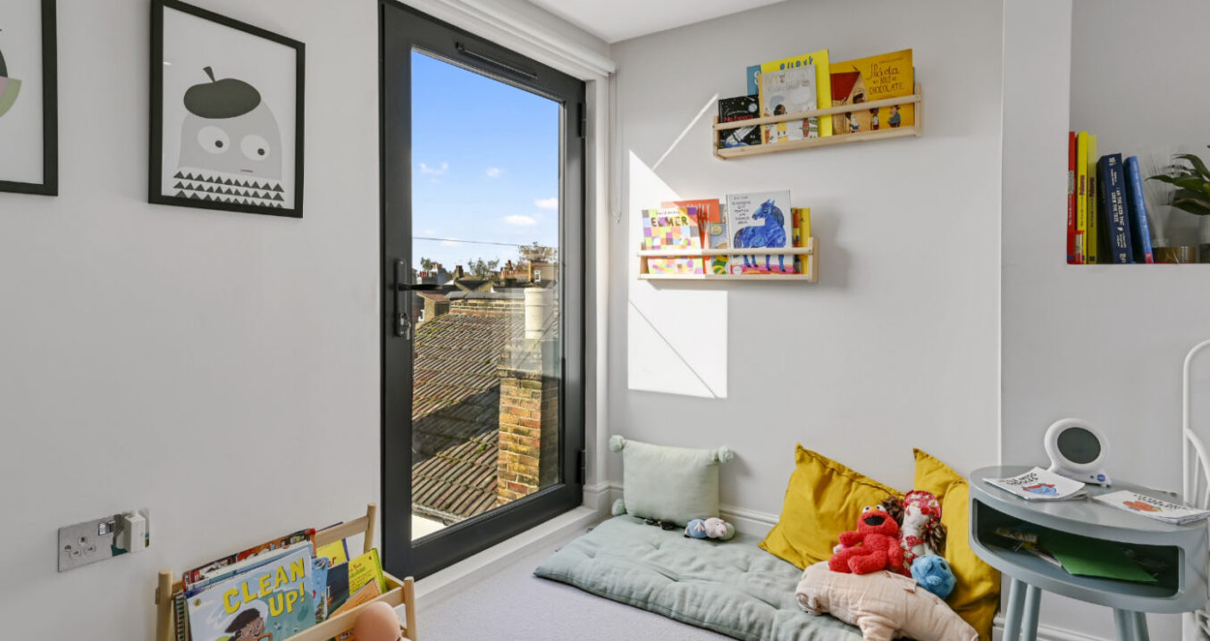 Light-filled children’s bedroom with bi-fold doors, reading nook and storage in a Walthamstow loft conversion