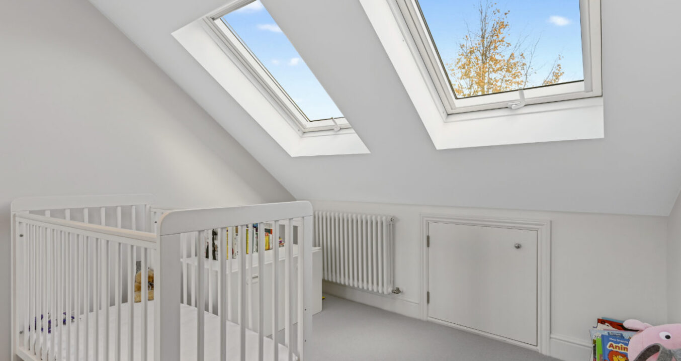 Bright nursery bedroom with two large roof windows and white cot in a Walthamstow E17 loft conversion
